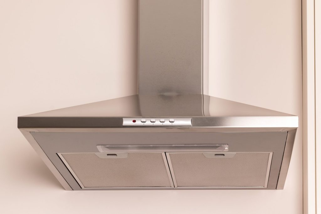 A stainless chimney hood against a plain wall.